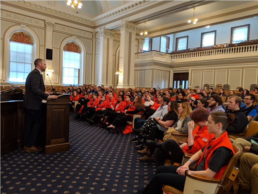 a speaker stands at a podium in front of a large audience