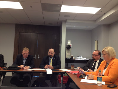a photo of people sitting around a u-shaped conference table